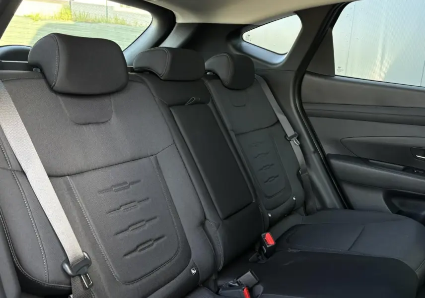 Vue intérieure des sièges arrière noirs du Hyundai Tucson 2025, avec appuie-têtes et ceintures visibles côté droit.