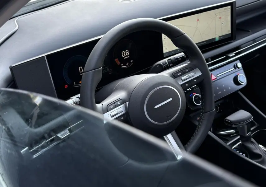 Vue rapprochée de l'intérieur du Hyundai Tucson 2025, volant cuir noir et tableau de bord numérique avec écran tactile large.