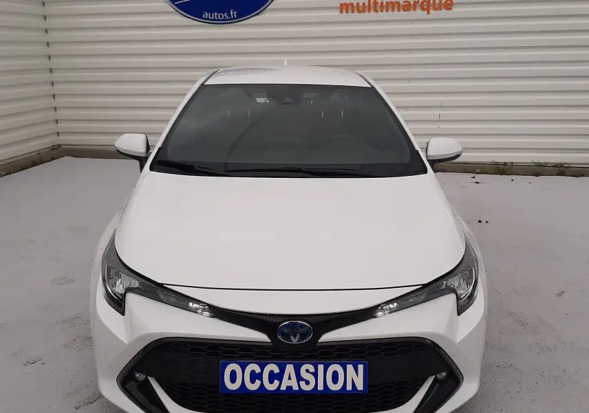 Vue frontale d'une Toyota Corolla blanche 122 CH Dynamic hybride essence avec plaque "OCCASION" visible.