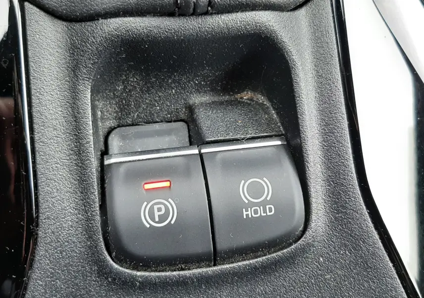 Gros plan sur les boutons de frein à main électronique et hold dans l'habitacle noir d'une Toyota Corolla blanche 2022.