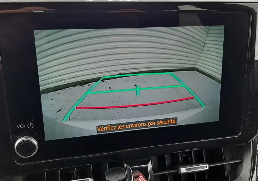 Écran central de la Toyota Corolla blanche 2022 montrant la caméra de recul avec lignes de guidage vertes et rouges.