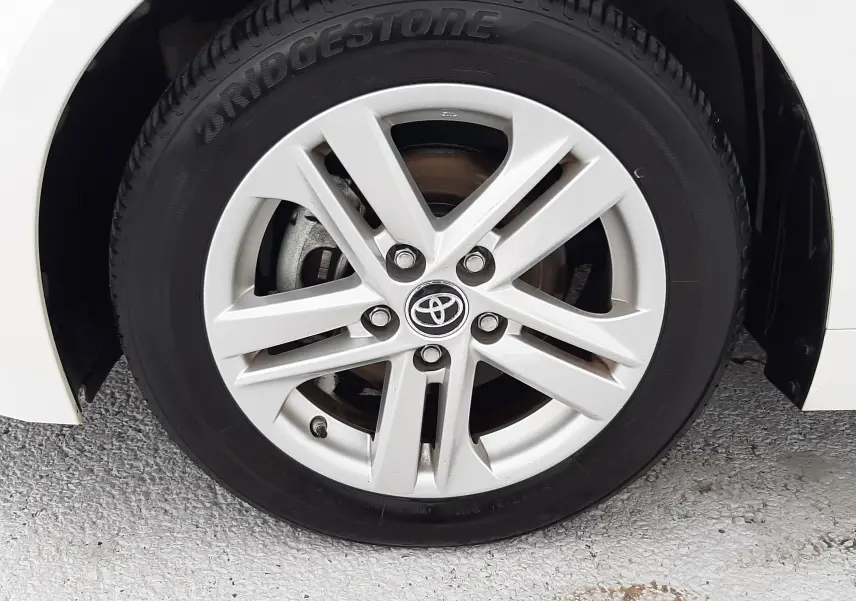 Gros plan sur la roue avant droite blanche d'une Toyota Corolla 122 CH Dynamic avec jante alliage et logo Toyota central.