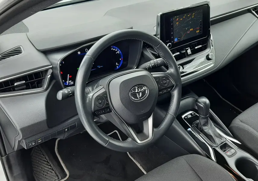 Vue intérieure côté conducteur de la Toyota Corolla 122 CH Dynamic 2022 blanche, tableau de bord et écran tactile visibles.