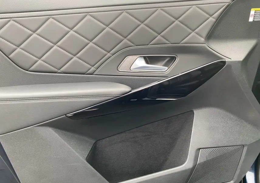 Gros plan sur la garniture de porte côté droit du DS7 2024 en cuir noir matelassé avec insert laqué noir.