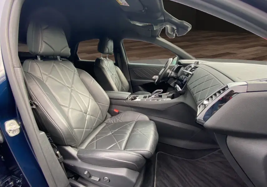 Vue intérieure côté conducteur du DS7 2024 bleu Eclipse, mettant en valeur la sellerie cuir électrique noire et le tableau de bord raffiné.