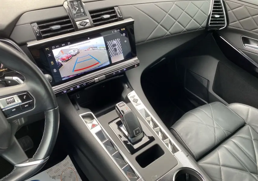 Vue intérieure du poste de conduite du DS7 Bleu Eclipse, mettant en valeur la sellerie cuir noire, la montre BRM et l'écran tactile central.