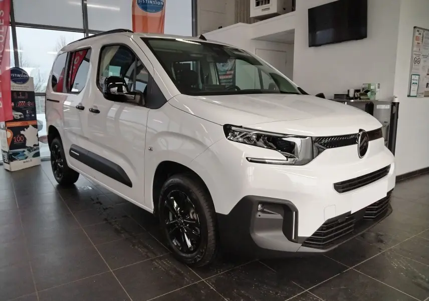 Citroën Berlingo blanc vue 3/4 avant droit en intérieur, avec jantes alu noir Starlit et rails latéraux couleur carrosserie.