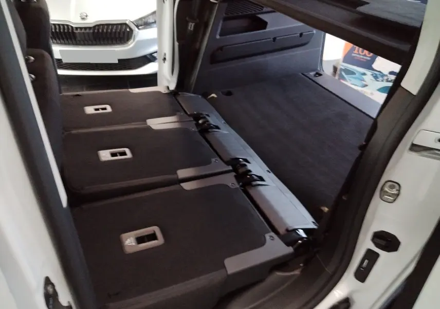 Vue intérieure arrière du Citroën Berlingo blanc 2025, sièges arrière rabattus et coffre spacieux visible.