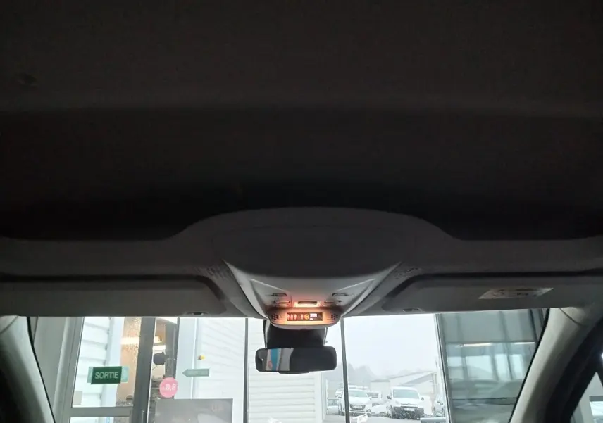 Vue intérieure avant du Citroën Berlingo blanc 2025, montrant le plafonnier et le rétroviseur central allumé.