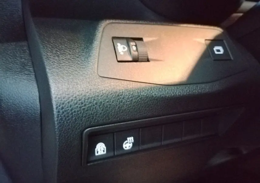 Gros plan sur les commandes intérieures du tableau de bord du Citroën Berlingo blanc, avec réglage des phares et sièges chauffants.