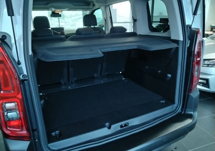 Vue arrière du coffre ouvert du Citroën Berlingo blanc 2025, montrant l’espace de chargement et la tablette cache-bagages.