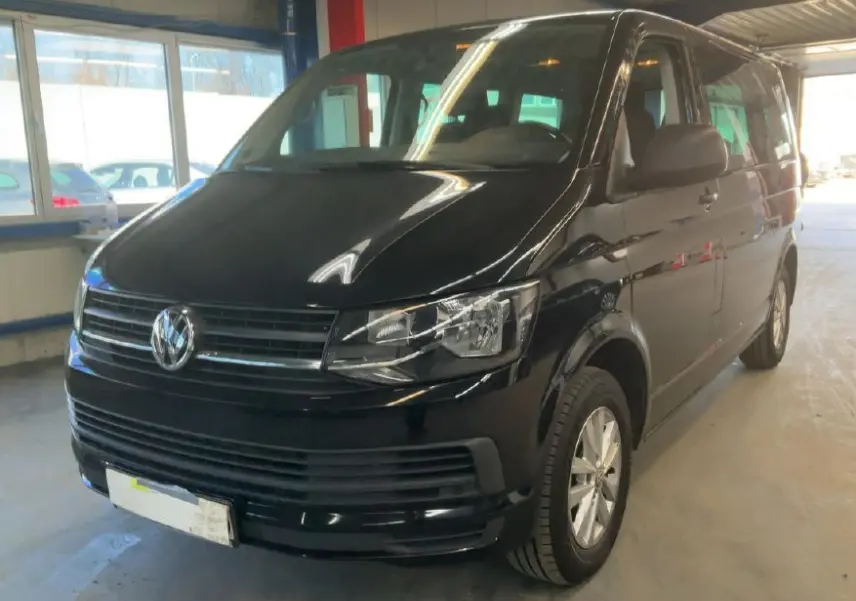 Volkswagen Multivan T6 noir vu en 3/4 avant droit dans un garage avec éclairage intérieur chaud.