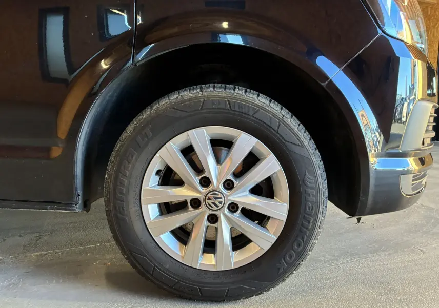 Gros plan sur la roue avant droite d’un Volkswagen Multivan noir T6 avec jante argentée et pneu Hankook.