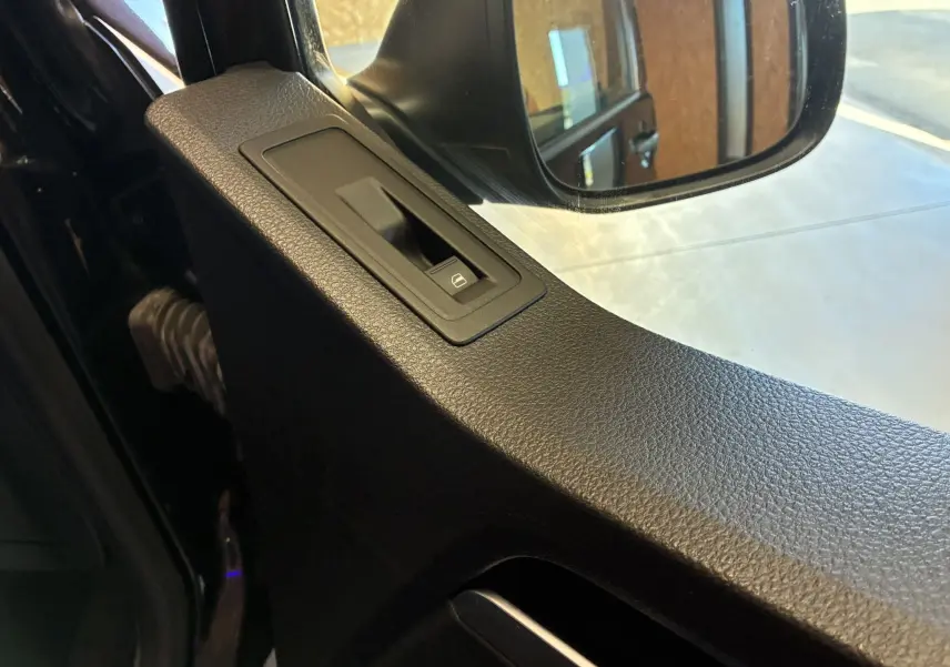 Détail de l’interrupteur de lève-vitre côté conducteur sur la portière noire d’un Volkswagen Multivan T6 2015.