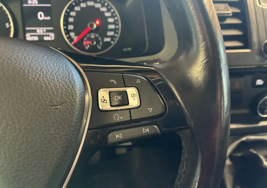 Gros plan sur le volant noir du Volkswagen Multivan T6 avec commandes intégrées et tableau de bord en arrière-plan.