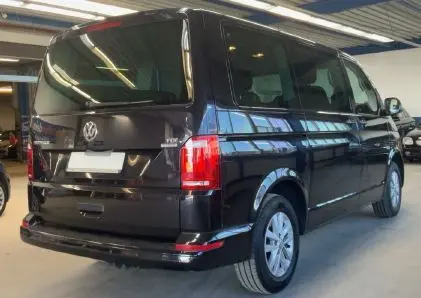 Vue de profil côté gauche d’un Volkswagen Multivan T6 noir, stationné en intérieur avec jantes alliage visibles.