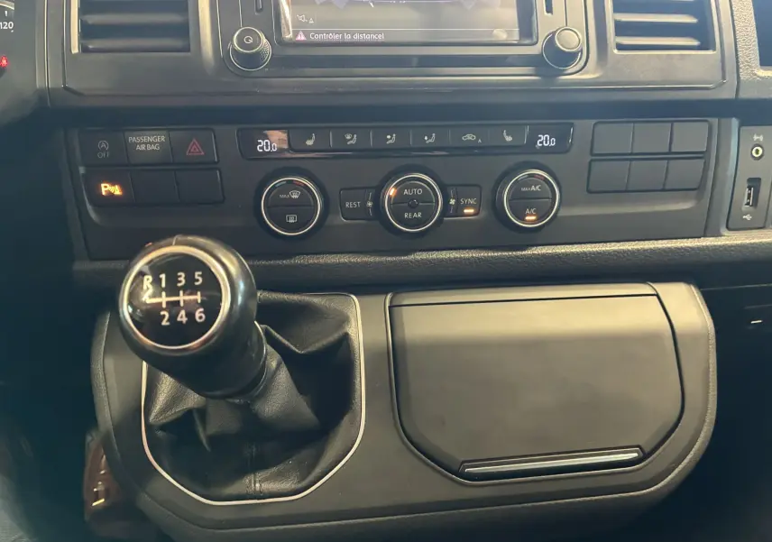 Vue rapprochée de la console centrale du Volkswagen Multivan T6 noir, mettant en valeur le levier de vitesses manuel et les commandes de climatisation.