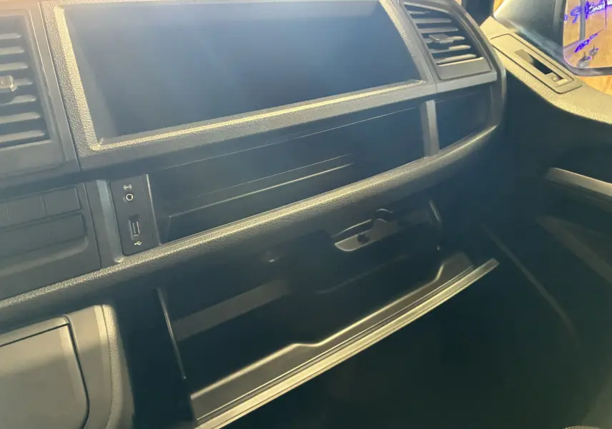 Intérieur noir du Volkswagen Multivan T6 PH.1 2015, vue du tableau de bord côté passager avec boîte à gants ouverte.