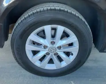 Volkswagen Multivan T6 noir vu en 3/4 arrière droit dans un garage avec reflets bleutés sur la carrosserie.