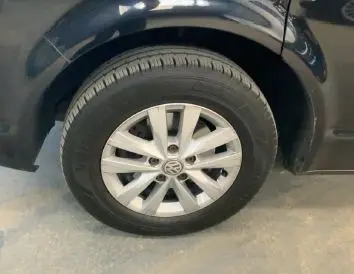 Vue de profil côté gauche d’un Volkswagen Multivan T6 noir de 2015 stationné en intérieur avec jantes alliage visibles.