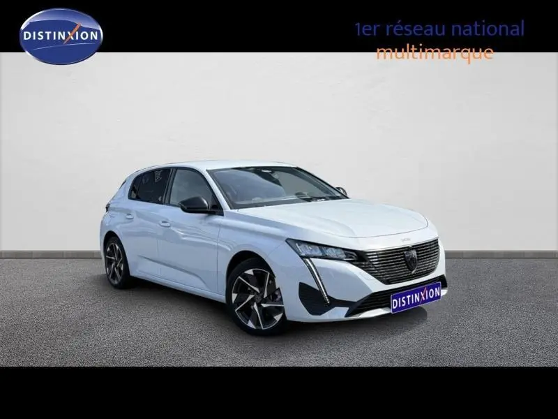 Peugeot 308 hybride blanche Okénite en 3/4 avant droit, avec calandre noire distinctive et jantes alliage.