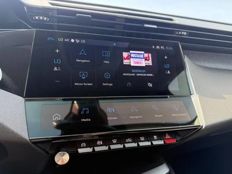 Vue rapprochée de l’écran tactile central et des commandes de la Peugeot 308 Hybrid 2025, tableau de bord moderne noir.
