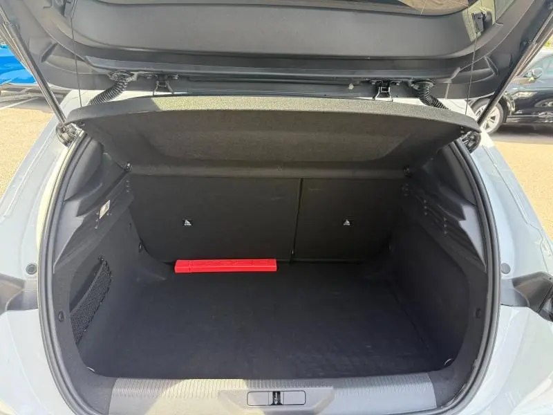 Coffre ouvert vu de l'arrière d'une Peugeot 308 blanche Okénite 2025, montrant un espace de rangement propre et vide.