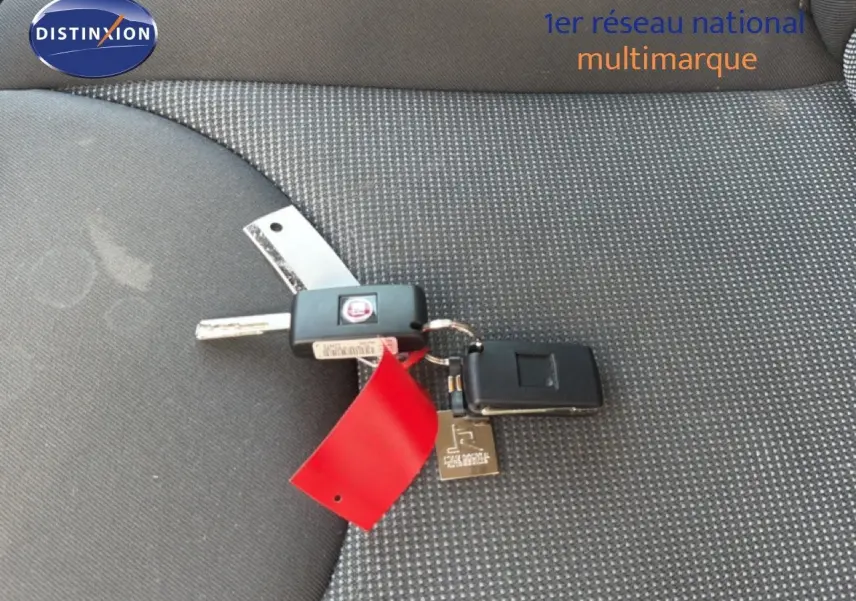 Clé de FIAT Scudo Fourgon gris métal 2016 posée sur un siège tissu gris à motifs fins.