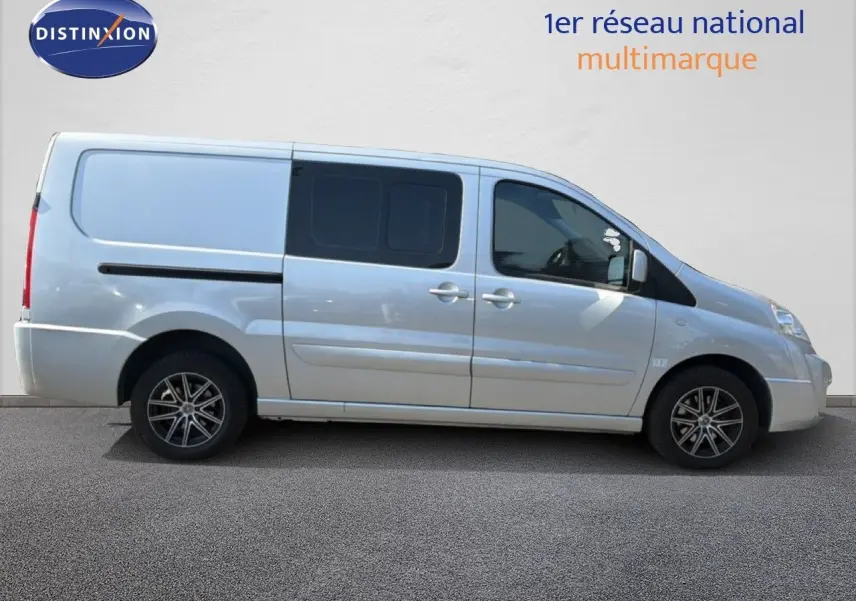 Vue de profil côté droit d’un FIAT Scudo Fourgon gris métal avec jantes alliage et vitres arrière teintées.