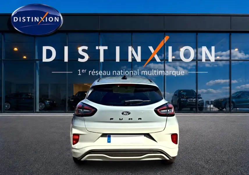 Vue arrière d'un Ford Puma gris cactus garé devant une vitrine avec logo Distinxion.