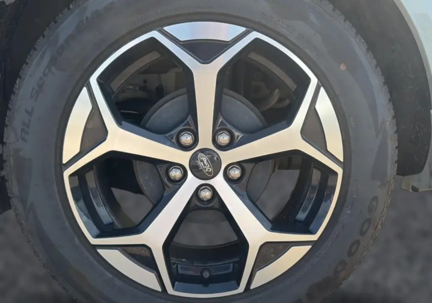 Gros plan sur la jante alu noire et argentée d’un Ford Puma gris cactus avec logo Ford au centre.