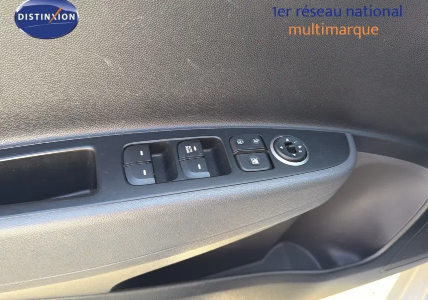 Gros plan sur la commande des vitres et rétroviseurs côté gauche d'une Hyundai i10 blanche 2018.