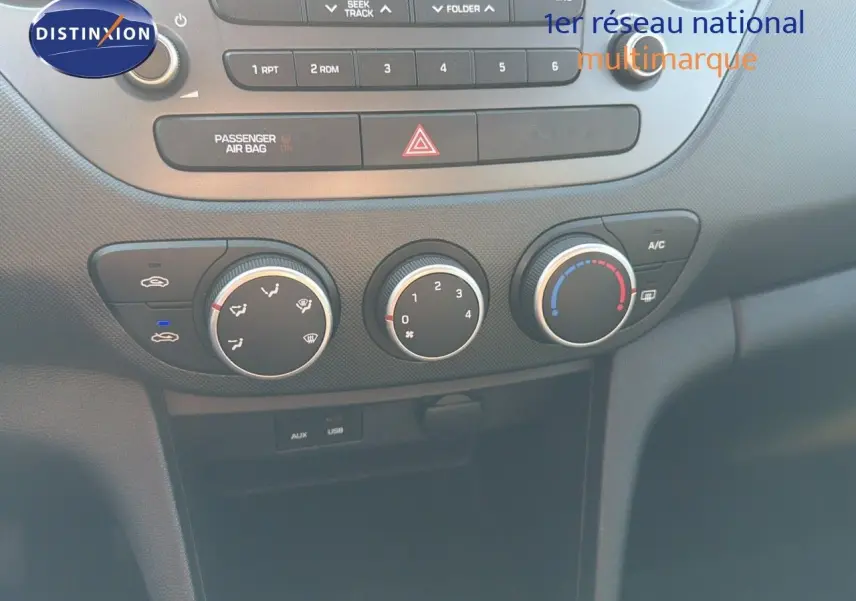 Gros plan sur la console centrale de la Hyundai i10 blanche 2018, montrant les commandes de climatisation et la radio.