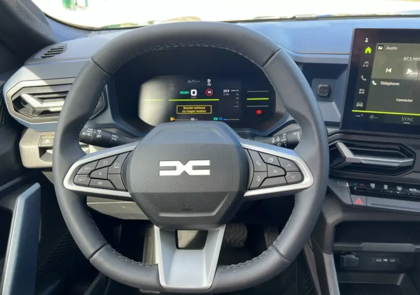 Vue intérieure centrée sur le volant cuir du Dacia Bigster Hybrid 155, avec tableau de bord numérique et écran tactile.