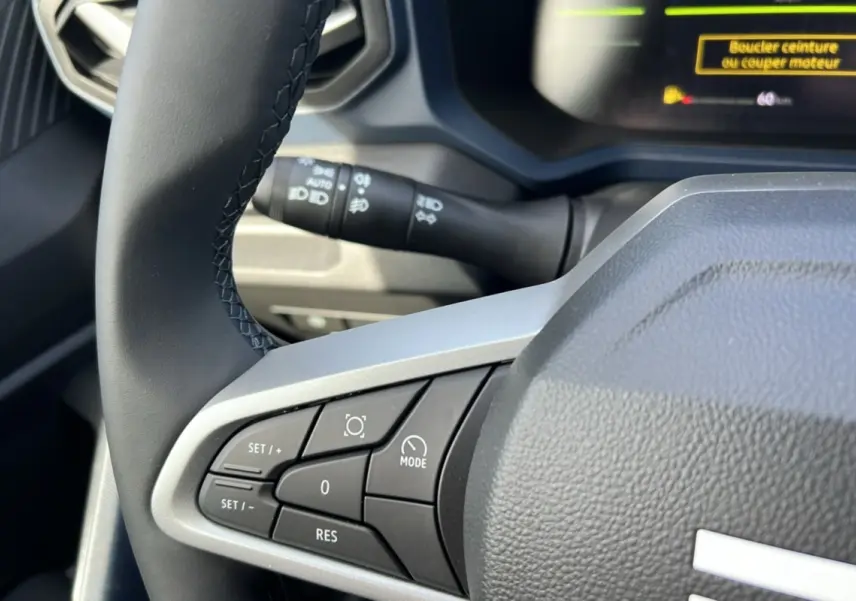 Gros plan sur le volant cuir noir du Dacia Bigster Hybrid 155 Expression Plus, avec commandes intégrées visibles.