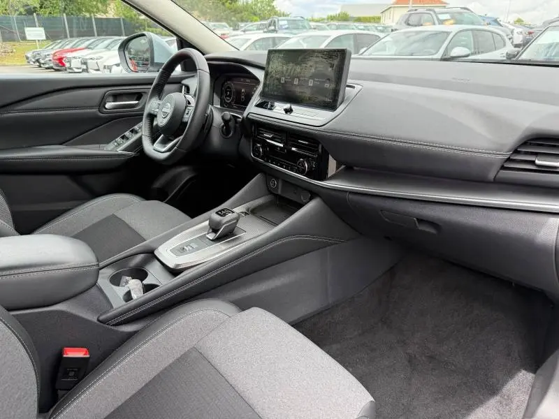 Vue intérieure côté conducteur du Nissan Qashqai 2025, tableau de bord moderne avec écran tactile et volant cuir multifonction.