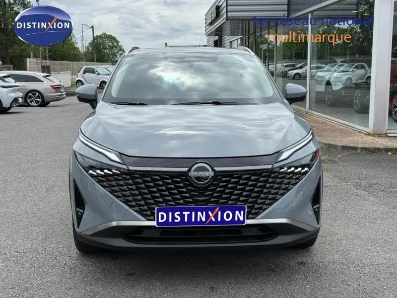 Vue avant frontale du Nissan Qashqai 2025 gris Argile avec calandre noire texturée et phares LED fins.