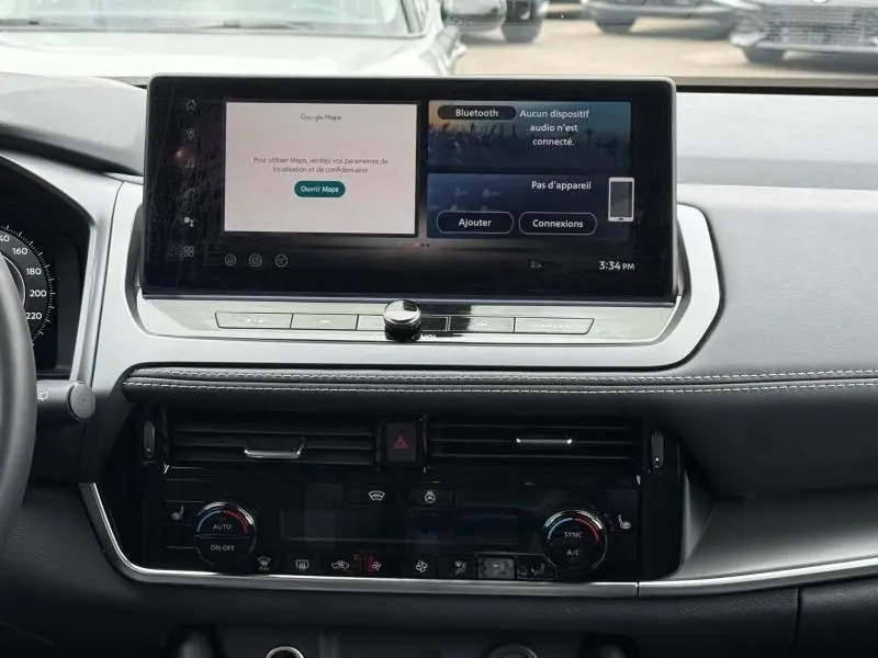 Vue intérieure du tableau de bord du Nissan Qashqai 2025 avec écran tactile multifonction et commandes climatisation.