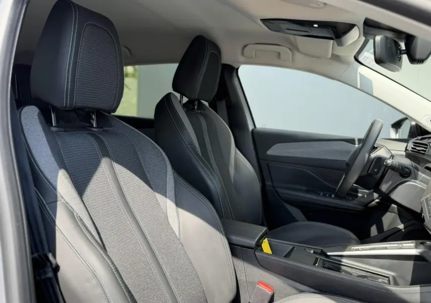 Vue intérieure de profil droit des sièges avant en tissu et cuir noir de la Peugeot 308 2025 finition Allure.