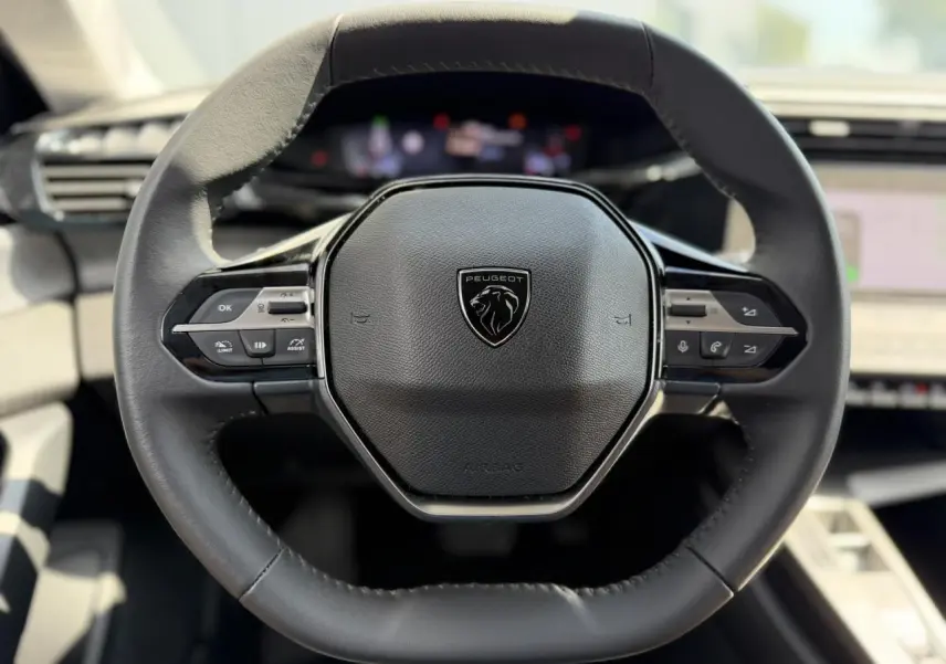 Volant en cuir noir de Peugeot 308 2025 vu de face, avec commandes intégrées et logo lion central.