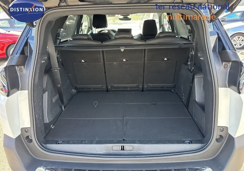 Coffre ouvert d’un Peugeot 5008 blanc nacré 2023, vue arrière montrant l’espace de chargement plat et les sièges rabattus.