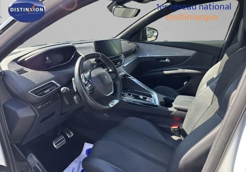 Vue intérieure côté conducteur du Peugeot 5008 blanc nacré 2023, avec tableau de bord moderne et volant compact multifonction.