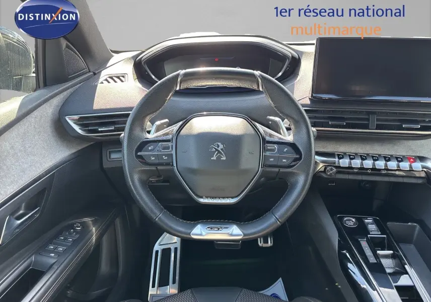 Vue intérieure frontale du poste de conduite du Peugeot 5008 GT 2023, volant compact cuir noir avec logo lion.