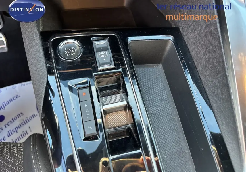 Vue rapprochée de la console centrale noire brillante du Peugeot 5008 GT 2023, avec sélecteur de boîte auto et bouton start.