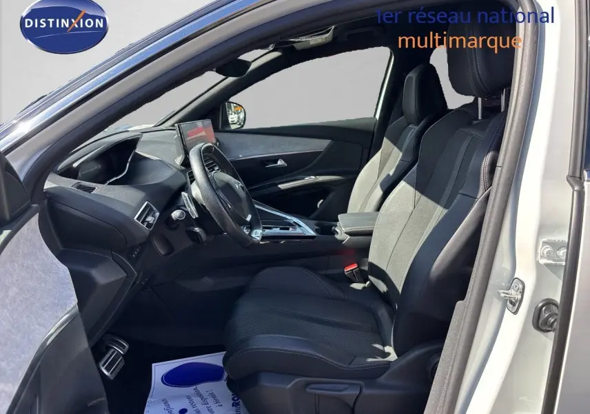 Intérieur côté conducteur d’un Peugeot 5008 blanc nacré 2023, sièges noirs en cuir et tableau de bord moderne.