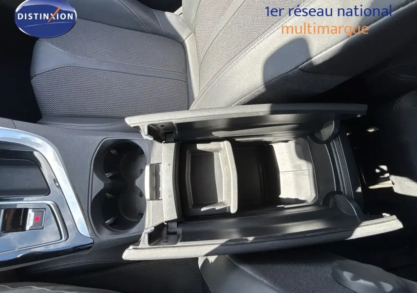 Vue plongeante sur l'accoudoir central ouvert et les sièges noirs en tissu du Peugeot 5008 Blanc Nacré 2023.