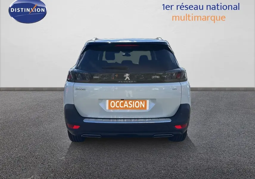 Vue arrière d’un Peugeot 5008 blanc nacré 2023 avec feux arrière noirs et double sortie d’échappement.