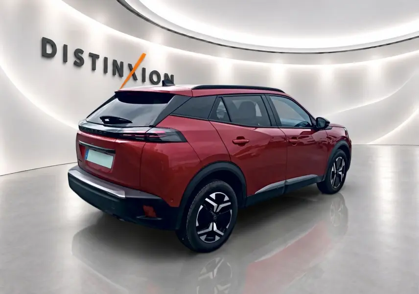 Peugeot 2008 rouge elixir vue 3/4 arrière droit, jantes alu noires et toit noir contrasté en showroom lumineux.