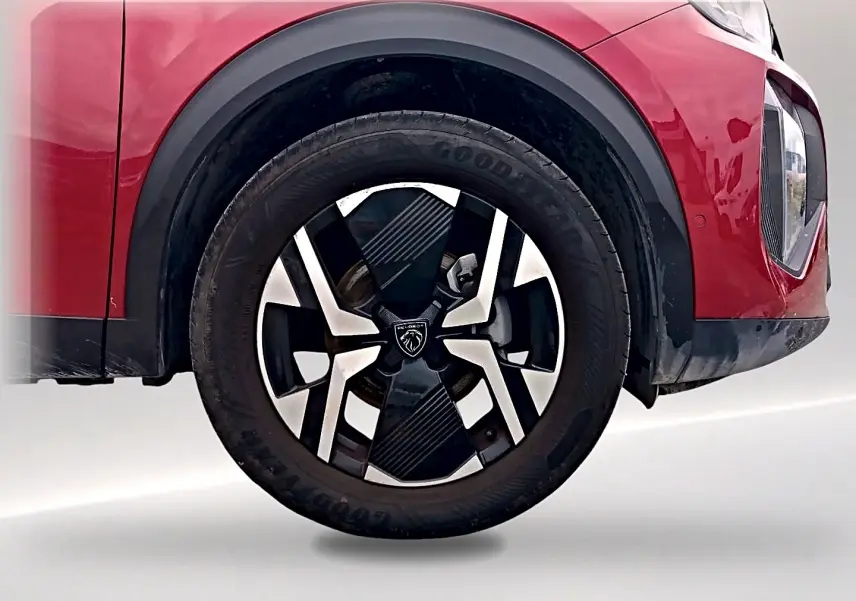 Gros plan sur la roue avant droite rouge elixir du Peugeot 2008 1.2 100 allure avec jante alu distinctive.