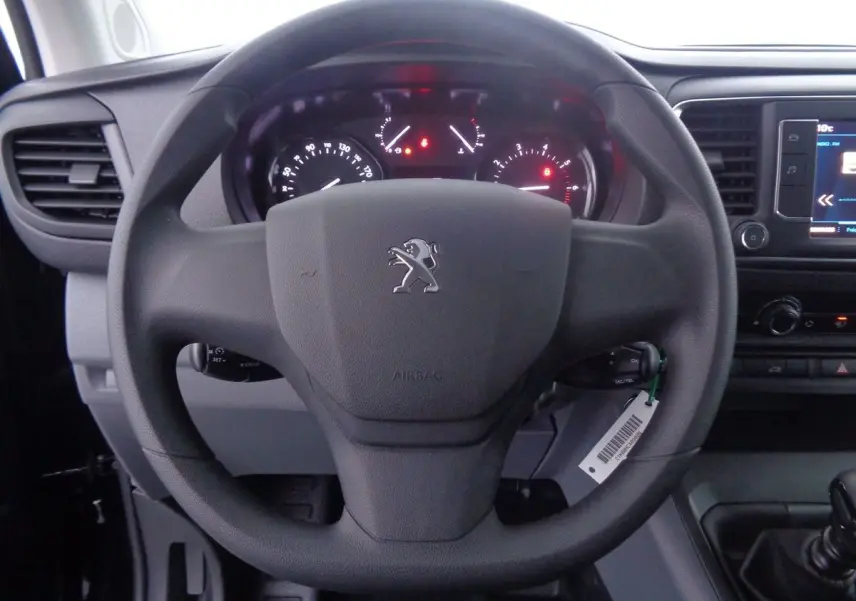 Vue rapprochée du volant noir du Peugeot Expert Fourgon 2022 avec tableau de bord et écran multimédia visibles.